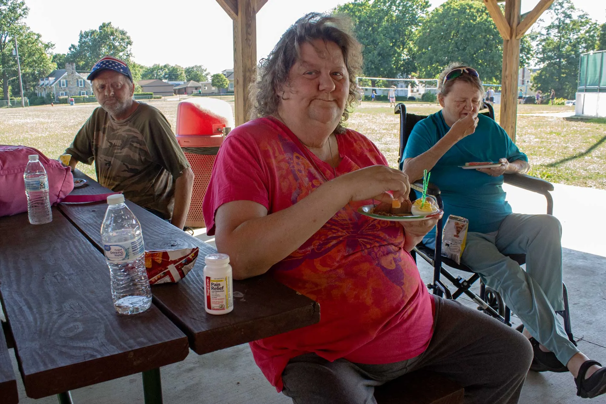 Woman looks up from a plate of food under a pavilion.