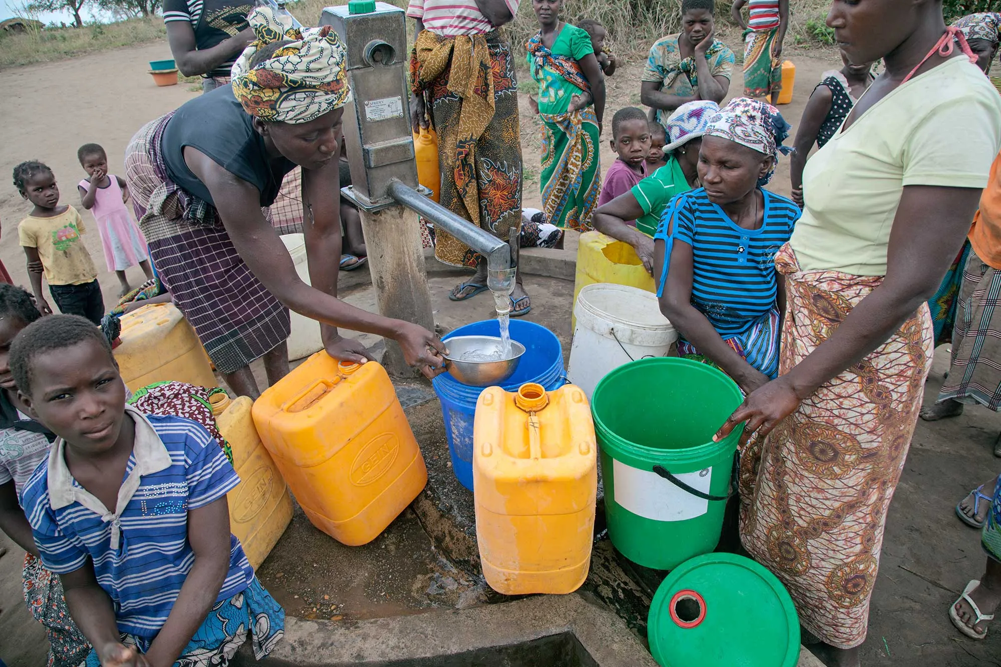 Women cluster around a stand pipe drawing water